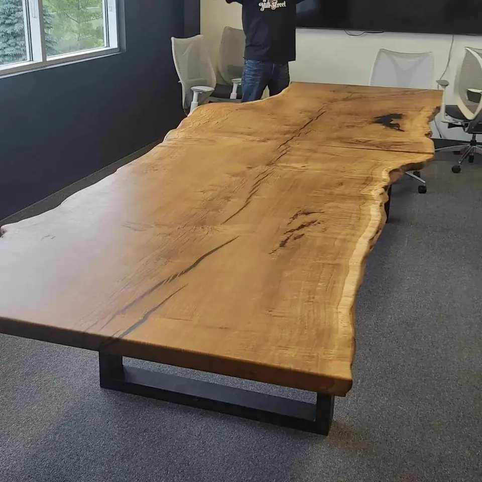 A finished live edge conference table on a black steel base
